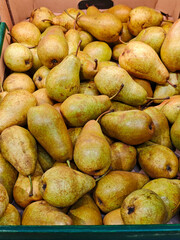 Fresh, ripe conference pears in a cardboard crate at the supermarket. A healthy and natural fruit background for concepts of grocery shopping, nutrition, and organic produce.