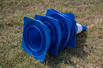 Stacked blue training cones resting on dry green grass under natural light outdoors