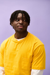 Fototapeta premium Stylish young man exudes confidence in vibrant attire against a soft purple backdrop