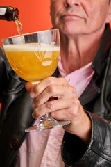 Closeup portrait of a elderly man in studio serving a beer