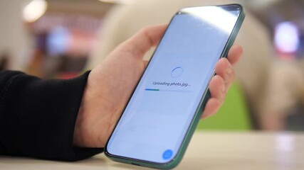 A woman's hands in a cafe setting successfully upload a photo file to cloud storage, receiving a confirmation notification. This scene represents modern digital workflows and seamless data management. - Powered by Adobe
