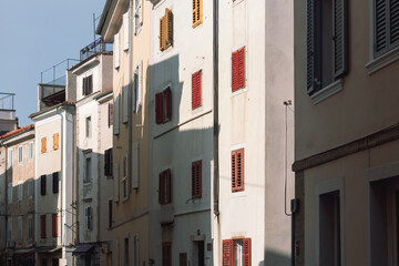 Colorful historic buildings with red and wooden shutters in narrow street Piran Slovenia