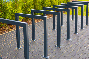 Fototapeta premium Modern metal bike racks lined in symmetry on a brick pavement after rain. A minimalist urban design promoting eco transport and sustainable city planning