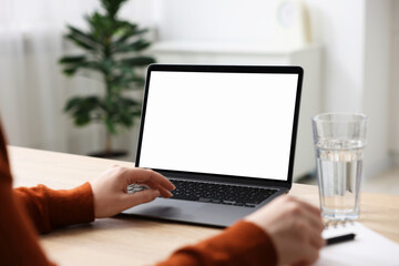 Woman working with laptop at wooden table indoors, closeup. Mockup for design