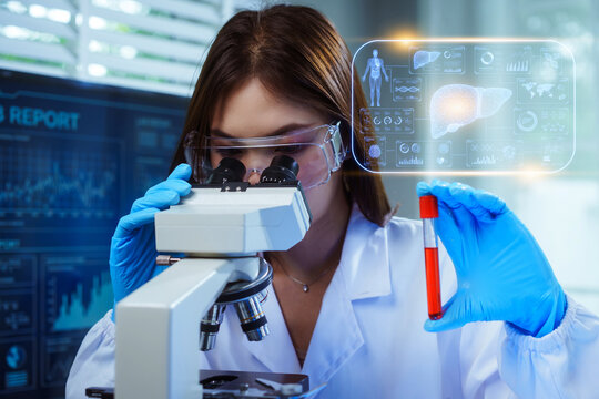 Asian female scientist simultaneously uses a microscope and holds a blood sample test tube, viewing a holographic overlay displaying human liver anatomy and diagnostic health data.