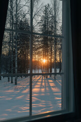Winter sunset shining through window on snowy landscape