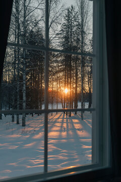 Winter sunset shining through window on snowy landscape