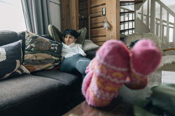 Young girl relaxing on sofa wearing pink woolen socks in winter chalet