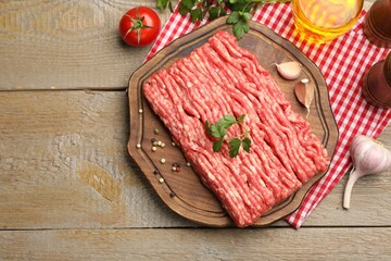 Raw minced meat with parsley and spices on wooden table, flat lay
