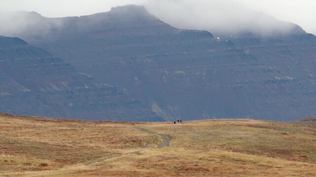 People hiking in Iceland huge mountain background autumn