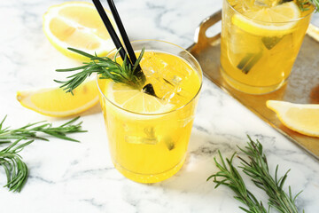Glasses of tasty cocktails with lemon and rosemary on white marble table, closeup