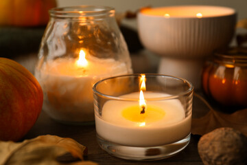 Autumn composition with burning candles and pumpkins on table, closeup