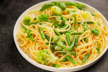 Spaghetti vegetables green peas, broccoli, string beans, kohlrabi vegetarian pasta tasty snack fresh delicious gourmet food background on the table rustic top view copy space vegan food
