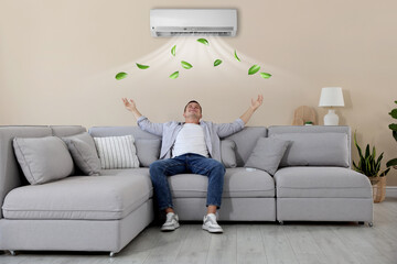 Man relaxing under air conditioner on sofa at home