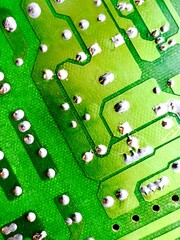 Close-up of green printed circuit board with soldered joints and conductive tracks, electronic hardware macro