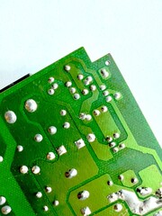 Green printed circuit board corner with visible solder points and copper traces, isolated macro close-up