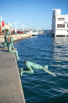 Santander, Spain &ndash; Nov 19, 2021: The famous 'Los Raqueros' monument by sculptor Jose Cobo on the waterfront of Santander, with the Real Club Maritimo building in the background.