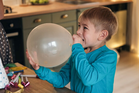 Family Fun Children Joyfully Blowing Up Balloons. Kids inflating balloons, prepare for birthday party. 3,6, 14 years old siblings racing blowing balloon, decorate the room. Bonding time together. Joy