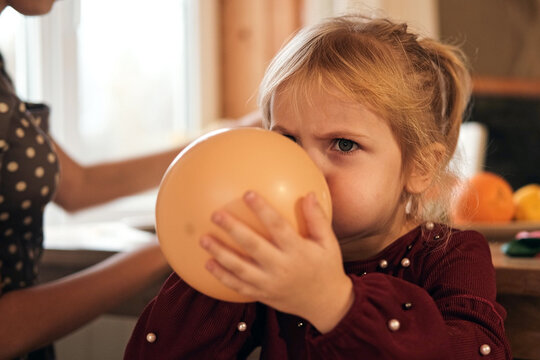 Family Fun Children Joyfully Blowing Up Balloons. Kids inflating balloons, prepare for birthday party. 3,6, 14 years old siblings racing blowing balloon, decorate the room. Bonding time together. Joy - Powered by Adobe
