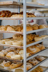 A variety of fresh baked goods and cakes on metal baking trays in a bakery cart