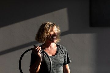 Portrait of a smiling senior woman dressed in sportswear during a Pilates class with a hoop in a small gym