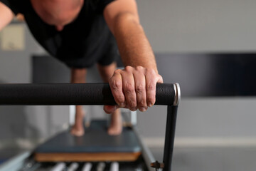 Detail of a man's hand using a reformer machine during a Pilates session