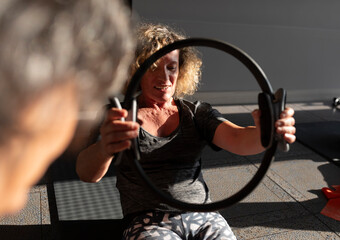 The Pilates instructor encourages her student during a Pilates exercise with a hoop in her hands