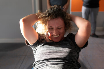 A cheerful senior woman does Pilates exercises in a small gym in her town