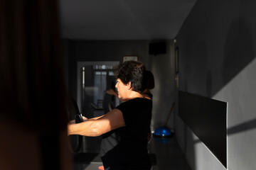 A group of women of various ages perform stretching and balance exercises with hoops at the end of a Pilates class