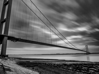 Fototapeta premium Black and white long-exposure image of the Humber Bridge stretching across the estuary at sunrise
