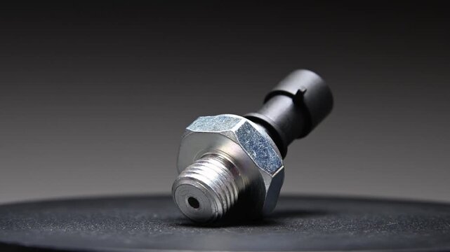 The engine oil pressure sensor rotates against a black gradient background. The sensor is a new spare part.