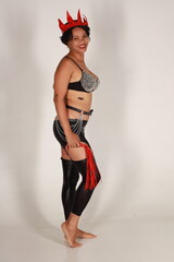 Beautiful young dark haired woman in leather lingerie with whip in her hands on white background