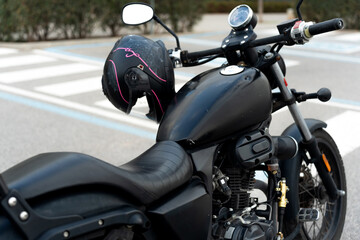 Black motorcycle with pink helmet for woman on handlebars