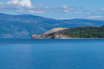 KRK Island, Vrbnik, Croatia - April 19, 2025: Cityscape. View of the coastline, rocky beach, and mountains