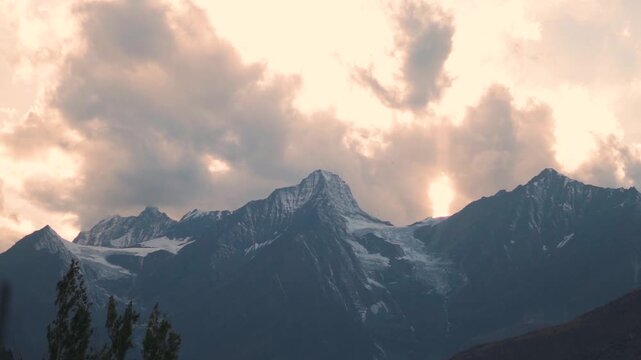 Landscape shot of orange clouds above the snowy Himalayan mountain peak during the sunset as seen from Keylong in Lahaul and Spiti district, Himachal Pradesh, India. Scenic view of sunset in autumn.