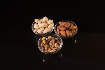 Cashew, Almond, and Pistachio in Three Small Glass Bowls on Dark Background — Healthy Dry Fruits and Nutrition Concept