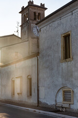 Golden hour sunlight streams past an old church, highlighting its textured walls and a fascinating vintage clock. Concept of time, history, and travel.