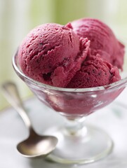 close-up of dragon fruit ice cream or sorbet in a elegant glass bowl, with a spoon resting beside it, highlighting its refreshing qualities and natural vibrant color. The background is softly 