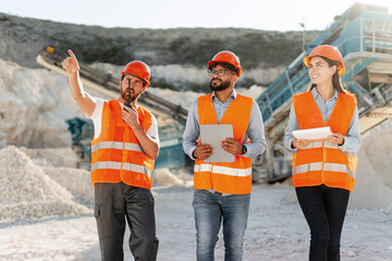 Smiling engineers in safety gear communicating and planning project at worksite