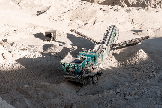 Fototapeta Industrial rock crusher working at limestone quarry surrounded by rocks and gravel