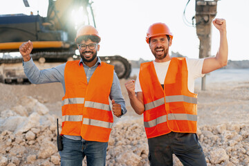 Happy construction workers celebrating success at worksite