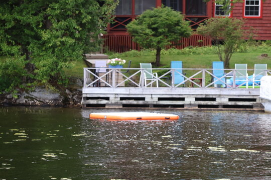 A view of an peaceful lakeside dock with Adirondack chairs.