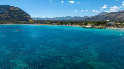 Aerial view of the blue and turquoise surface of the Mediterranean sea. In the background is Mondello Beach, located near Palermo, Sicily, Italy. 