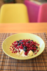 Homemade yoghurt with fresh berries and chia seeds in plate on a wooden table