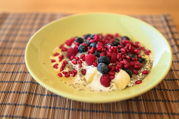 Homemade yoghurt with fresh berries and chia seeds in plate on a wooden table