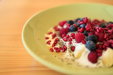 Homemade yoghurt with fresh berries and chia seeds in plate on a wooden table