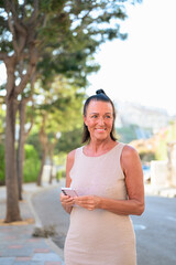 Portrait of smiling mature woman using mobile phone in the city