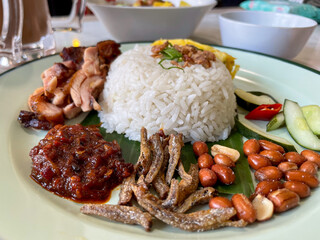 
Malaysian nasi lemak. It has various side dishes such as salted fish, fried peanuts, chicken rendang, dried tempeh sambal, pickles, and a sprinkling of savory fried onions on top of the rice