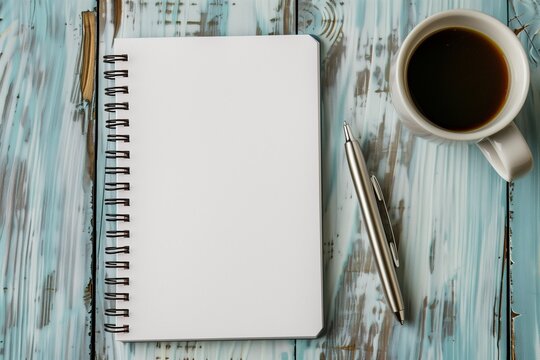 Top-down flat lay of blank spiral notebook on wooden desk, pen and coffee beside, minimal lifestyle scene mockup.