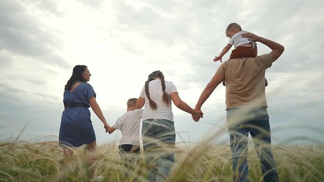 Family walking slowly through grass. Father carries happy son, mother beside holding child hand. Every boy, every kid feels safe. Each parent bonding. Strong walking bonding in loving family scene.